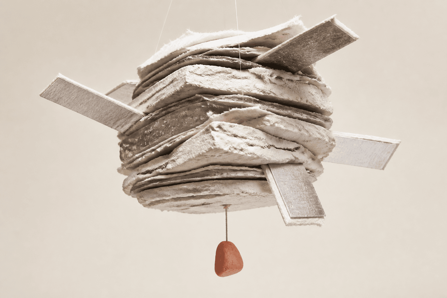 Illustration éditoriale générée montrant un faisceau suspendu de papier, plâtre, résine et aluminium, prolongé par quatre languettes et lesté par une petite pierre corail.