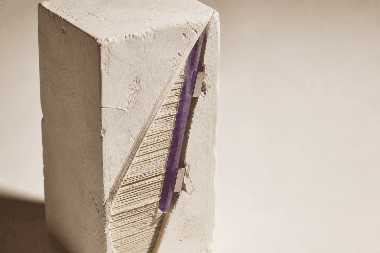Generated close-up of an ivory-plaster monolith cut diagonally to reveal paper layers, a violet-glass blade and two aluminium gauges.